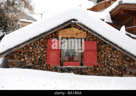 Un tradizionale chalet Svizzero nel villaggio alpino di Saas Fee contemplati nella fitta neve fresca Foto Stock