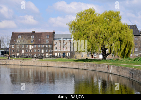 Parte del canale navigabile canalizzato River Lea Navigation presso gli edifici storici di grado i elencati sul sito del mulino ad acqua Three Mills Bromley di Bow East London UK Foto Stock