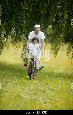 Uomo maturo e una ragazza equitazione biciclette Foto Stock