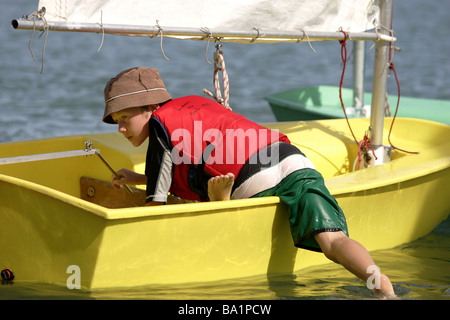 Un giovane marinaio si prepara per il lancio di un optimist dinghy a Nelson Yacht Club, Nuova Zelanda Foto Stock