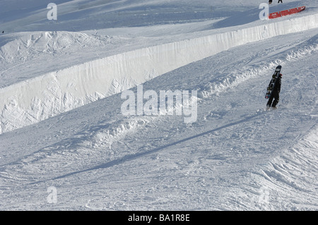 Un lone snowboarder a piedi fino al lato di un halfpipe in Saas Fee estate glacier ski area Foto Stock