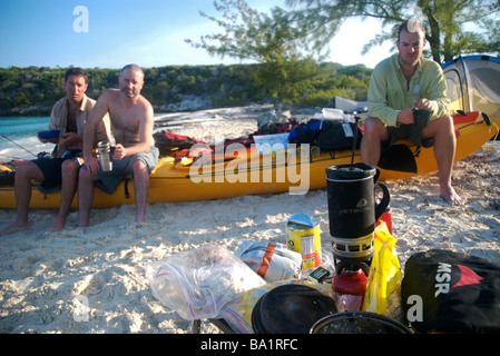 Un gruppo di mare kayakers attendere per il caffè per essere pronto su un kayak di mare spedizione nelle isole exuma, BAHAMAS Foto Stock