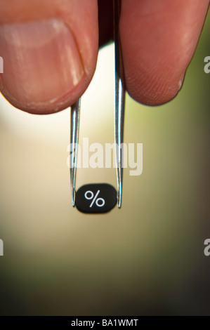 Stretta di mano con le pinzette tenendo premuto un tasto calcolatrice con il segno di percento. Foto Stock
