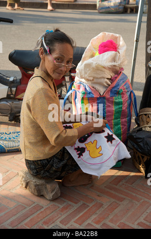 Una donna del Laos la cucitura un ricamo souvenir in Luang Prabang mercato notturno Laos Foto Stock