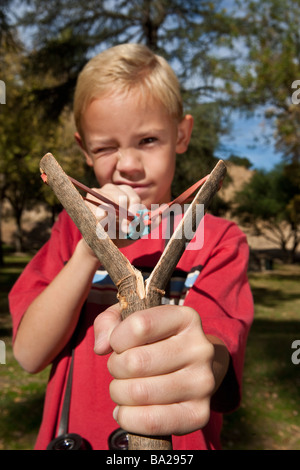 Ragazzo (7-9) utilizzando slingshot Foto Stock