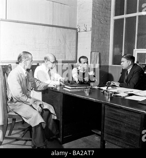 1950s, riunione intorno ad un ufficio, di responsabile dello stabilimento, caposquadra e rappresentante dei lavoratori, presso la Glacier Metal Company, Alperton, Inghilterra, Regno Unito. Foto Stock