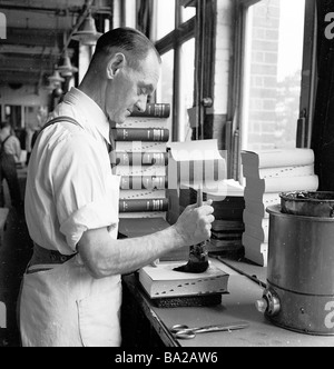 Lavoratore di sesso maschile nella rilegatura libro sezione del HWV print factory, mediante incollaggio a mano il coperchio sul nelle pagine interne della copertina rigida con un libro, l'Inghilterra degli anni cinquanta Foto Stock