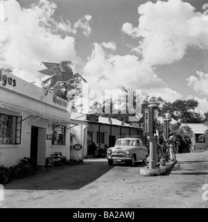 1950s, storico, una piccola auto Austin si rifornisce in una stazione di servizio Mobilgas rurale a Kenmaur, Matabeleland, in quella che era allora la Rhodesia, ora Zimbabwe. Foto Stock
