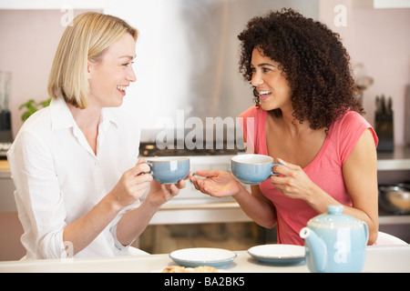 Amici di sesso femminile gustando il tè e i biscotti a casa Foto Stock