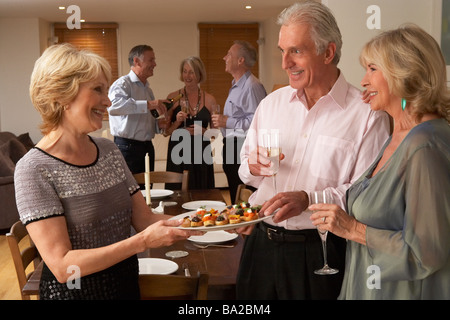 Donna che serve antipasti ai suoi ospiti a una cena Foto Stock