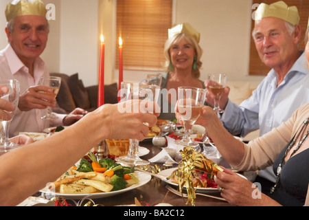 Amici indossando cappelli di partito a una cena Foto Stock