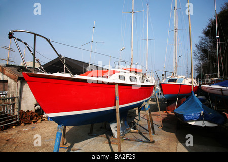 Barche a vela in preparazione per la nuova stagione in un cantiere in porto a porto di Weymouth Foto Stock