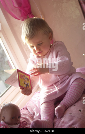 Ragazze foto-libro davanzale guardare siede persone toddler bambino 1-2 anni abbastanza biondo-corpi interni a home vivai di sale giochi Foto Stock