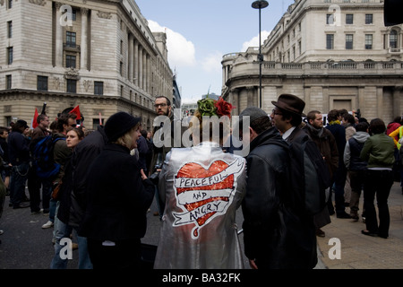 Una donna che indossa un cappotto con le parole "pacifiche e arrabbiato' al G20 di protesta a Londra presso la banca di Inghilterra Foto Stock