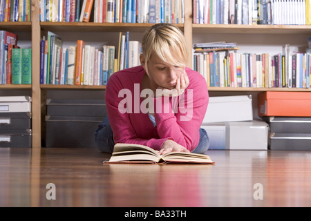 Donna giovane piano giace prenota legge scaffale dettaglio persone serie 20-30 anni studente bionda scolaretta poggia testa approfondisce Foto Stock