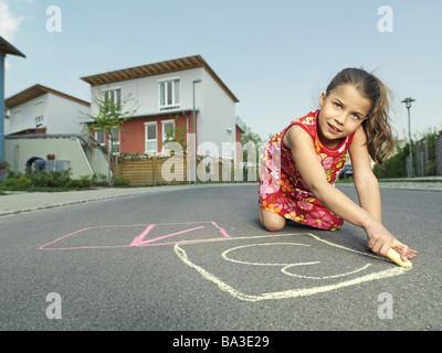 Le ragazze si inginocchia chalk scatole vernici di strada persone serie infanzia bambini 9 anni abito estivo con i capelli lunghi brunette sguardo fotocamera Foto Stock