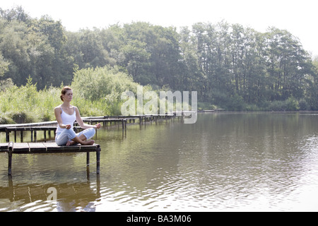 Giovane donna siede a ponte serie di meditazione persone abbastanza-corpi 24 anni 20-30 anni dai lunghi capelli bruna ABBIGLIAMENTO SPORTIVO ABBIGLIAMENTO SPORTIVO Foto Stock