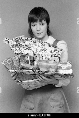 Negli anni settanta, foto in bianco e nero, Natale, giovane donna porta un sacco di regali di Natale nelle braccia, di età compresa tra i 18 e i 25 anni, Monika Foto Stock