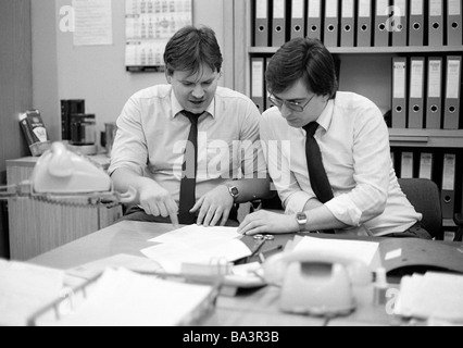 Ottanta, foto in bianco e nero, economia, lavoro, occupazione, due addetti ufficio presso la scrivania in un talk, telefoni, file cabinet, di età compresa tra i 25 ed i 35 anni, Uwe, Wolfgang Foto Stock