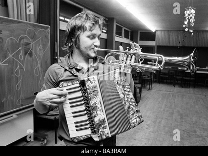 Negli anni settanta, foto in bianco e nero, cultura, musica, umorismo, giovane uomo gioca in una berlina trombone e fisarmonica in una sola volta, di età compresa tra i 20 e i 25 anni Foto Stock