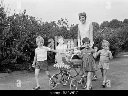 Negli anni settanta, foto in bianco e nero, formazione ed educazione, l'educazione dei bambini, Kindergarten, infermiera per bambini, fostress, di età compresa tra i 18 e i 20 anni, i bambini e i ragazzi e le ragazze di età compresa tra 3 e 5 anni il bambino nel passeggino, di età compresa tra 1 e 2 anni, a piedi, camminando a piedi, passeggiando Foto Stock