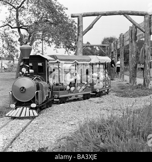 Negli anni settanta, foto in bianco e nero, le persone, i bambini e i ragazzi e le ragazze guidare da un modello ferroviario, parco giochi per bambini di età compresa da 4 a 7 anni Foto Stock