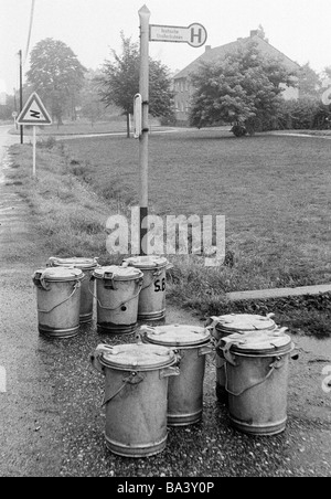Negli anni settanta, foto in bianco e nero, umorismo, la fotografia del prodotto, otto pattumiere stand ad una fermata in attesa per la raccolta Foto Stock