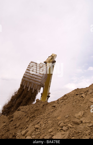 Benna di un escavatore il dumping delle rocce e del suolo su scorte Foto Stock