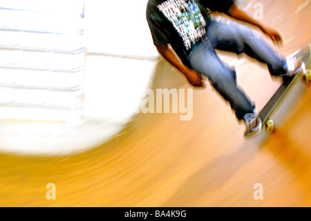 Guidatore di skateboard etnica gare di lato verso il basso di uno skateboard velodrome in uno skateboard park Foto Stock