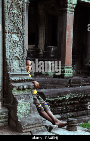 Ragazzo cambogiano di relax presso il Ta Phrom tempio di Angkor, Cambogia Foto Stock