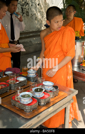 Un novizio monaco buddista si prepara una bevanda per i frati anziani al Wat Pho tempio di Bangkok Foto Stock