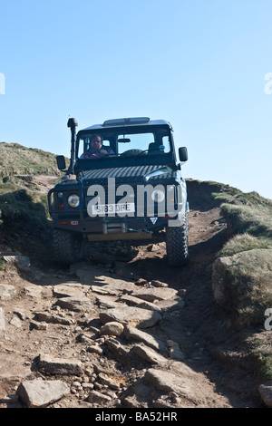 Land Rover Defender scende la via verso il basso il bordo stanage nel Derbyshire Peak District Foto Stock