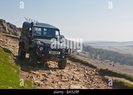 Land Rover Defender scende la via verso il basso il bordo stanage nel Derbyshire Peak District Foto Stock