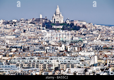 Basilica Sacré-Cœur Montmartre Paris France Skyline // PARIGI, Francia — la Basilica del Sacro Cœur (Basilique du Sacré-Cœur) a Montmartre è in primo piano da questa vista dalla cima della cattedrale di Notre Dame. Questa chiesa cattolica romana, un importante punto di riferimento, è situata sulla cima della Butte Montmartre, il punto naturale più alto di Parigi. La sua caratteristica cupola bianca e la sua facciata sono costruite in travertino Château-Landon, che naturalmente sbiancano con la pioggia. La basilica, consacrata nel 1919, è celebrata per il suo stile architettonico romano-bizantino. Offre un sorprendente contrasto visivo Foto Stock