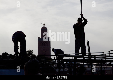 I titolari di stallo costruire i telai metallici dei loro banchi di cibo in preparazione della serata rush, Piazza Jemaa el Fna a Marrakech Foto Stock