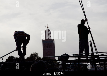 I titolari di stallo costruire i telai metallici dei loro banchi di cibo in preparazione della serata rush, Piazza Jemaa el Fna a Marrakech Foto Stock