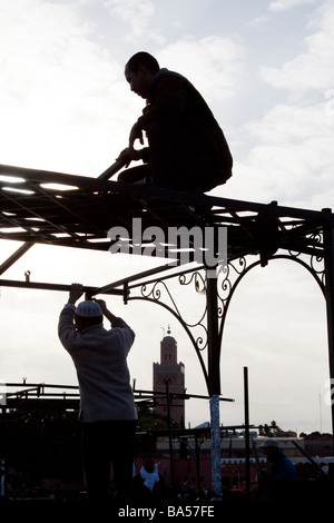 I titolari di stallo costruire i telai metallici dei loro banchi di cibo in preparazione della serata rush, Piazza Jemaa el Fna a Marrakech Foto Stock
