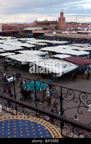 I turisti rilassarsi bevendo tè alla menta da una caffetteria con terrazza sul tetto che si affaccia sulla piazza Jemaa el Fna nella Medina di Marrakech Foto Stock