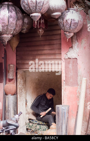 Giovane arabo marocchino in uomo Medina creazione di tradizionali oggetti di metallo a mano nel suo laboratorio colorati nei souks, Marrakech Foto Stock