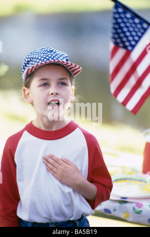 Ragazza al picnic con bandiera americana berretto da baseball con bandiera americana ritratto giuramento di fedeltà Foto Stock