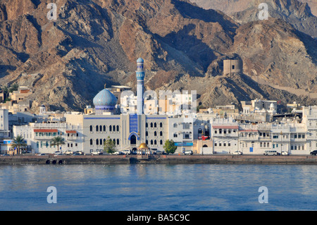 Strada lungomare Corniche sul Golfo di Oman e stretta striscia di sviluppo sfondo di parte della catena montuosa Hajar a Muttrah a Muscat Oman Foto Stock