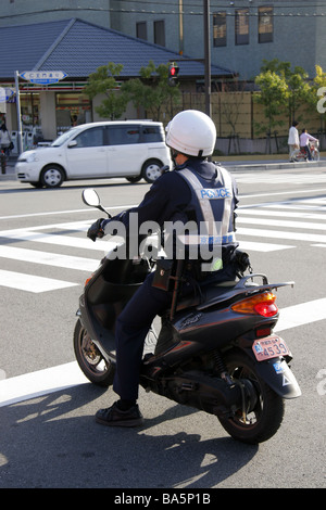 Giapponese ufficiale di polizia a cavallo di un ciclomotore a Kyoto in Giappone Foto Stock