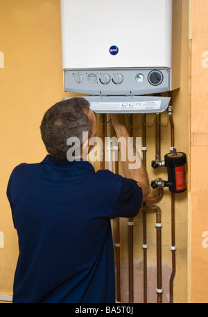 Plumber / ingegnere gas lavorando su un efficiente dal punto di vista energetico la condensazione Baxi caldaia gas Foto Stock