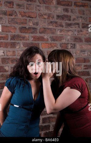 Il sussurro della donna in un'altra donna le orecchie Foto Stock