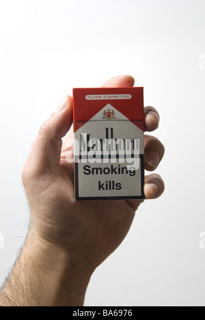Mano d'uomo tenendo un rosso sigarette Marlboro il pacchetto con il fumo uccide avvertenza Foto Stock
