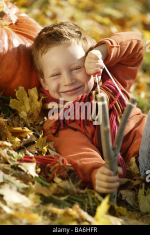 Dare nascita catapulta caduta delle foglie si trova mira allegramente sorride al di fuori della telecamera lo sguardo di bambino 5-8 anni pidocchio del jack-canaglia rosso-hairy Foto Stock