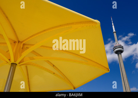 Giallo ombrellone in spiaggia urbana di hto park toronto con la CN Tower e cielo blu Foto Stock