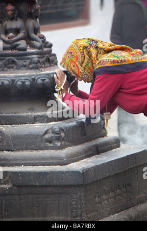 Donna pellegrino con testa sciarpa a Kathmandu Boudhanath pregando da statua e mulini di preghiera. Il Nepal Asia 90417 Nepal Foto Stock