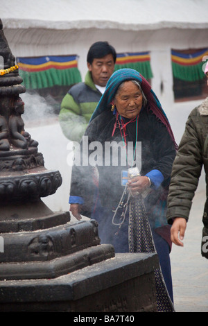 Le donne i pellegrini a Kathmandu Boudhanath pregando da statua, fumo e mulini di preghiera. Il Nepal Asia 90419 Nepal Foto Stock