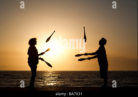 Due persone che l uomo e la donna giovane giocoleria con i club al tramonto sul lungomare di Aberystwyth Wales UK Foto Stock